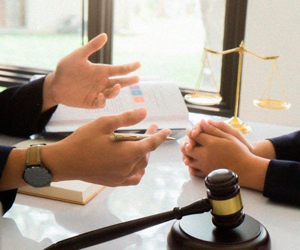 Um cliente sentado à frente de uma advogada especialista em Direito Previdenciário que o atende com atenção.